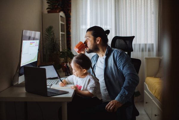 Dad and daughter researching how a money market account works with girl writing checks.